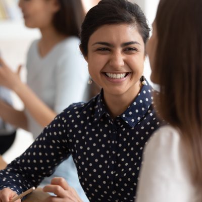 Girls students do common exercise task sitting at desk in classroom focus on smiling cheerful attractive indian ethnicity learner, concept of teamwork, preparation for exams and cooperative learning